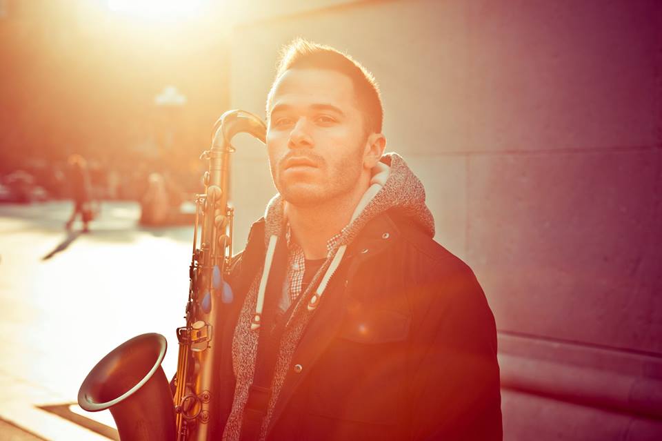 Ted Hadges holding a tenor saxophone in warm evening light